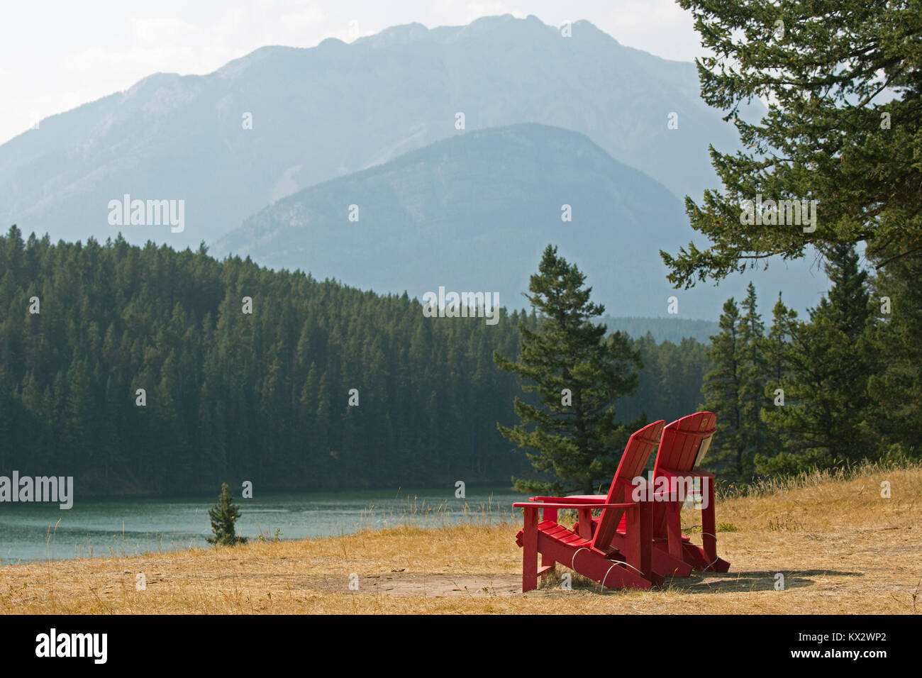 Deux chaises rouges surplombant le lac Johnson et les montagnes dans le parc national Banff Banque D'Images