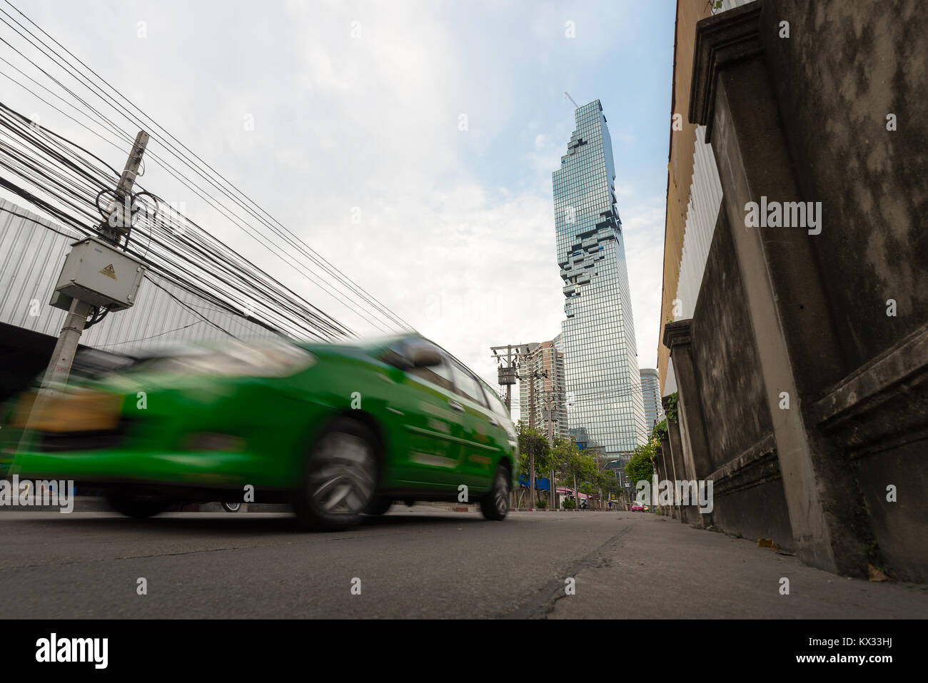 Un taxi vert Bangkok brouille passé sur la route loin de la Saint James immeuble gratte-ciel dans le Silom/Sathon quartier central des affaires de Bangkok, Thail Banque D'Images