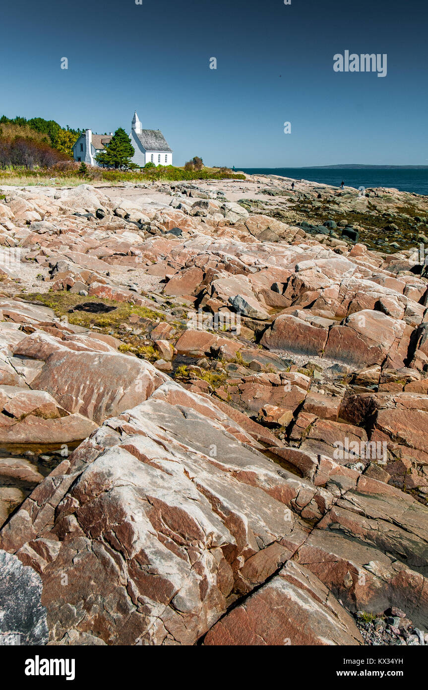 La petite église de Port-au-Persil derrière les rochers à marée basse, Québec, Canada Banque D'Images