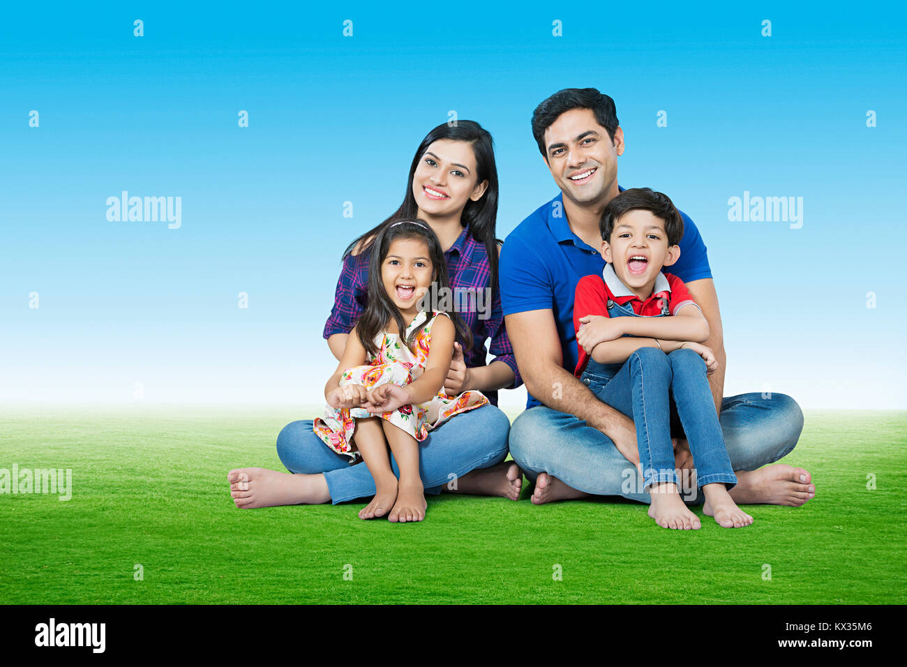 Famille heureuse, les parents et les enfants assis dans l'Herbe Parc Banque D'Images