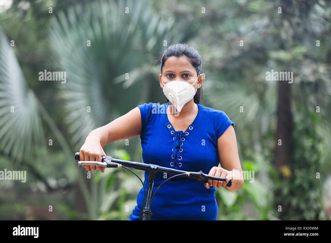 Jeune femme Équitation Parc Cycle masque la pollution atmosphérique Banque D'Images