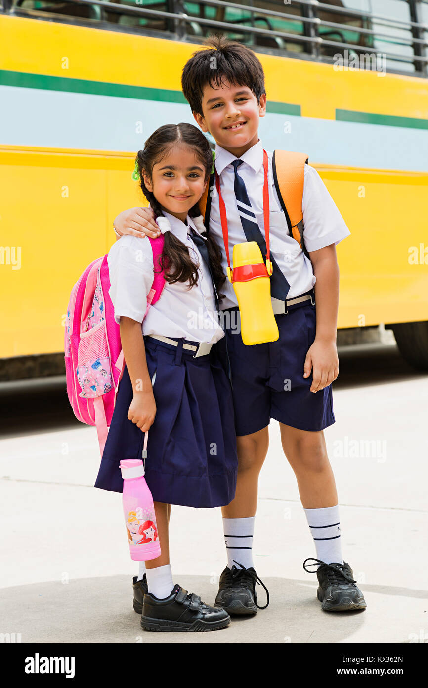 2 Smiling Indian School Kids ami Students Standing ensemble près de Bus Banque D'Images