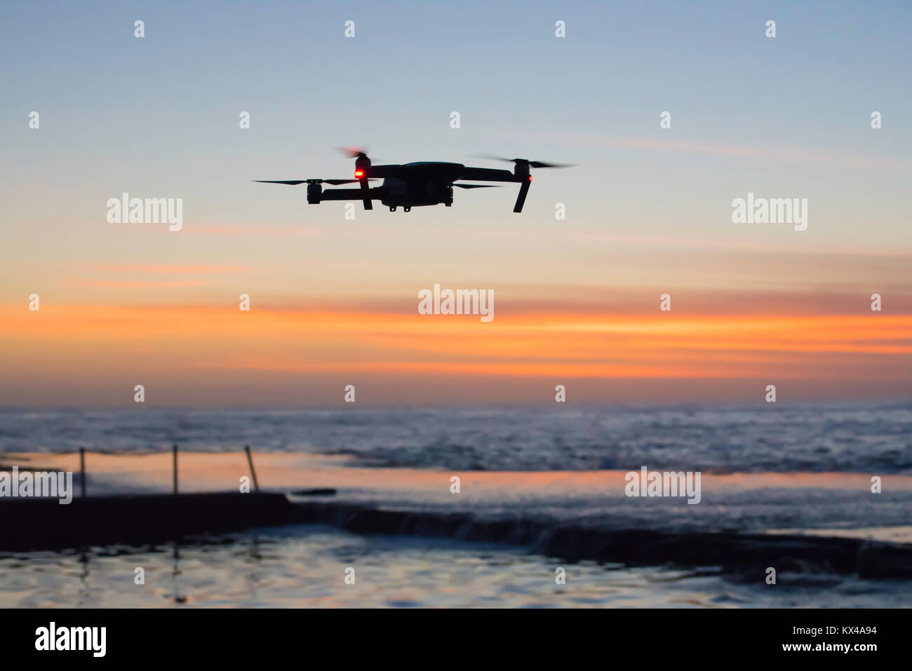 La silhouette d'un drone vole à basse altitude au-dessus d'une mer intérieure, près de Sydney, très tôt le matin en Australie Banque D'Images