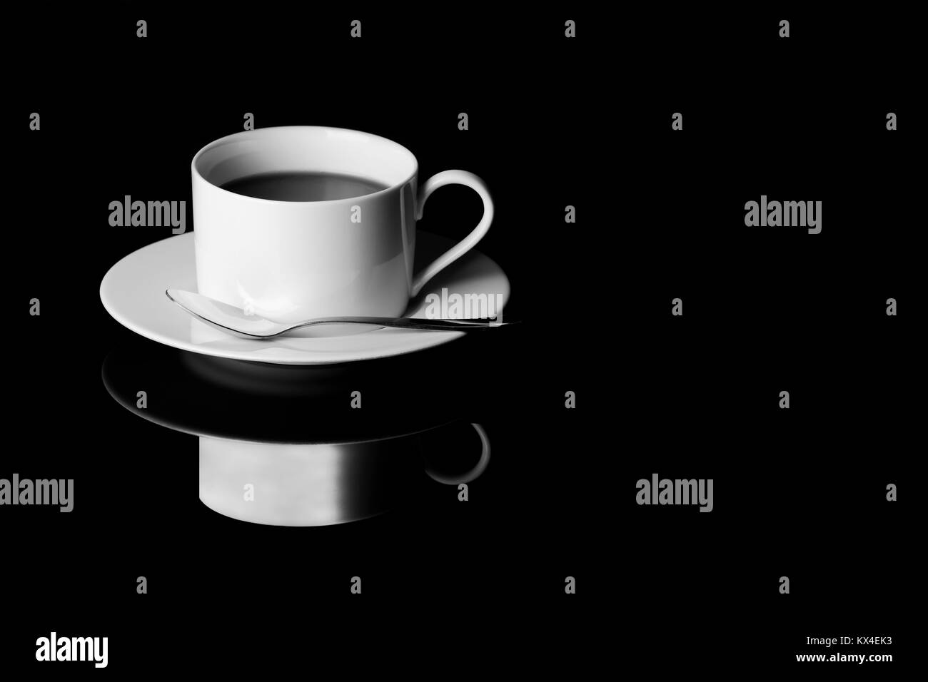 L'image d'une tasse de café noir en noir et blanc tourné sur un plateau en verre noir Banque D'Images
