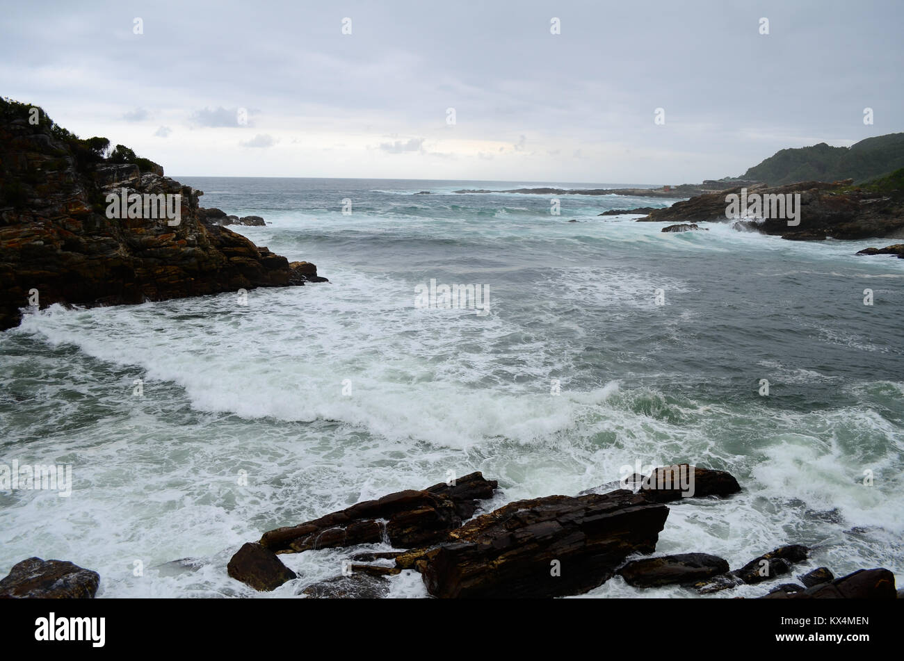 Vue sur la baie d'une côte rocheuse avec des vagues se briser contre les rochers au premier plan et sur la baie Banque D'Images