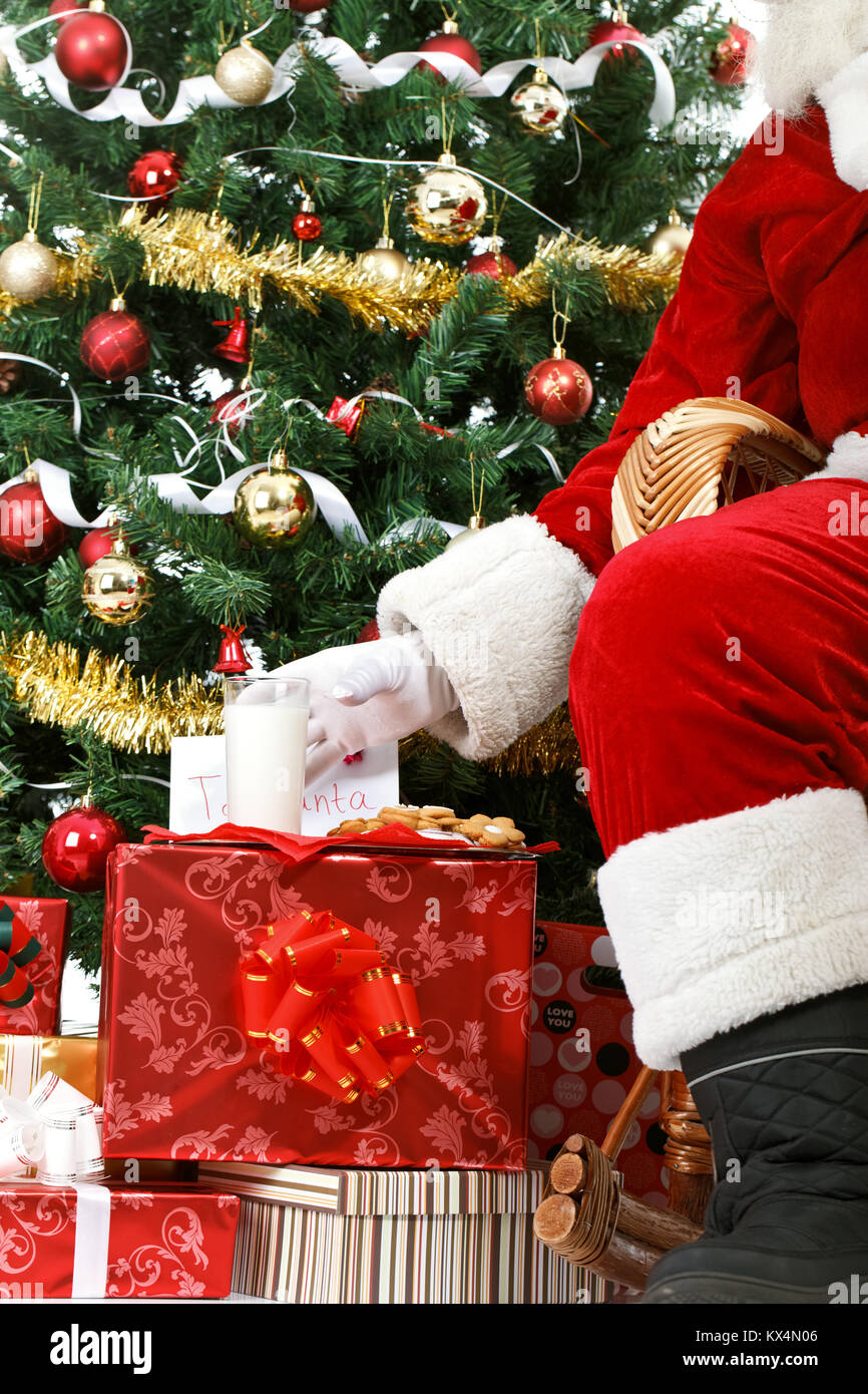 Le Père Noël prend un lait et des cookies laissés pour lui la veille de Noël comme un cadeau de remerciement pour laisse un présent à un enfant reconnaissant Banque D'Images