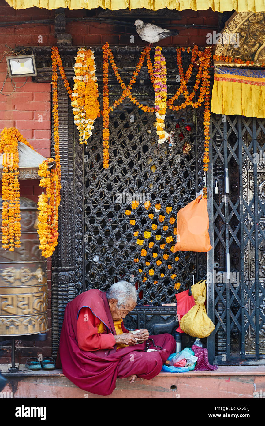 Ancien moine tibétain Stupa Boudhanath à mendicité entrée privée, Katmandou, Népal Banque D'Images