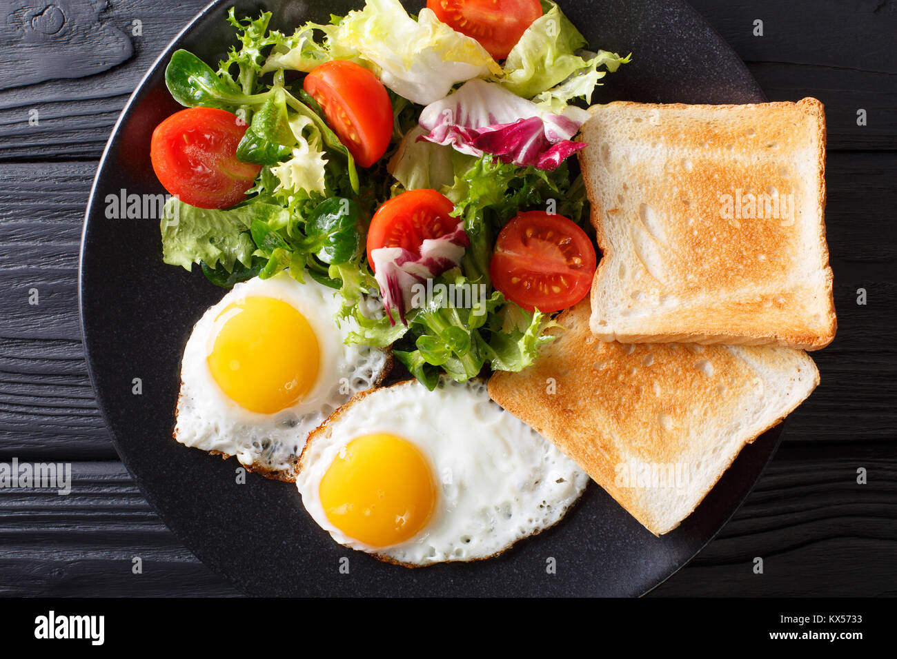 Petit-déjeuner des aliments biologiques : oeufs au plat avec une salade de légumes frais et de pain grillé sur une plaque sur la table. haut horizontale Vue de dessus Banque D'Images
