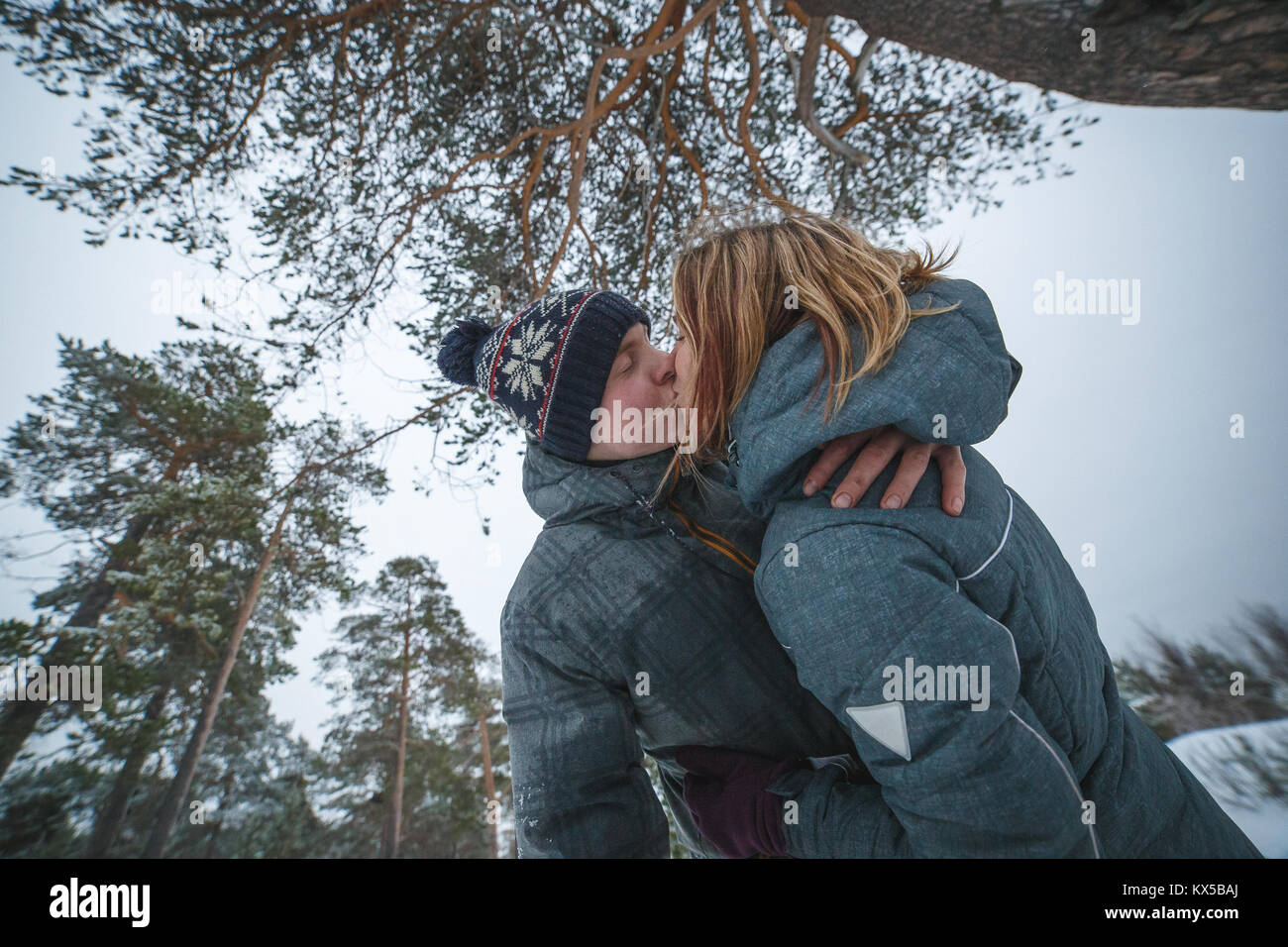 Jeune beau couple la pine tree in snowy winter forest Banque D'Images