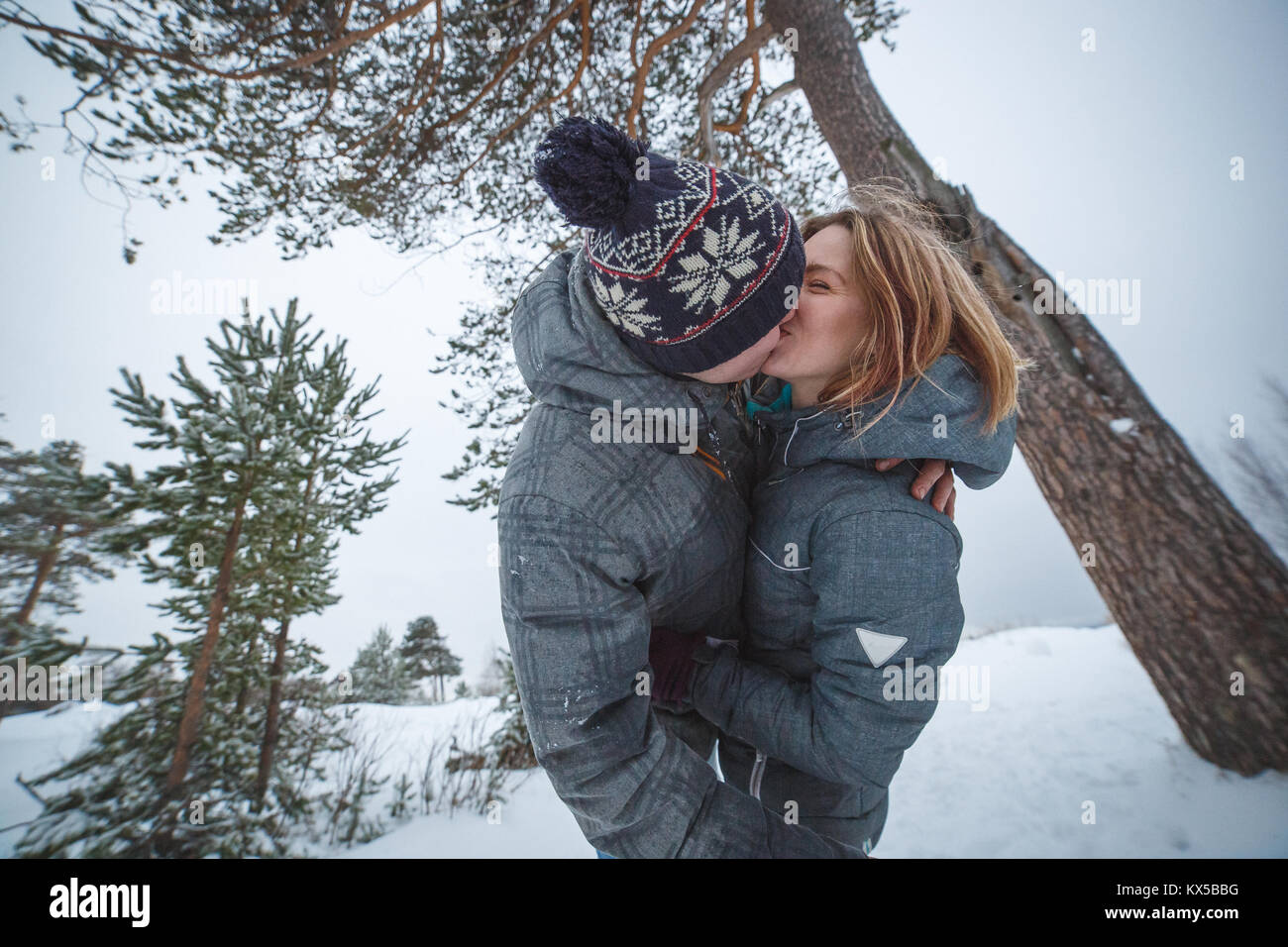 Jeune beau couple la pine tree in snowy winter forest Banque D'Images