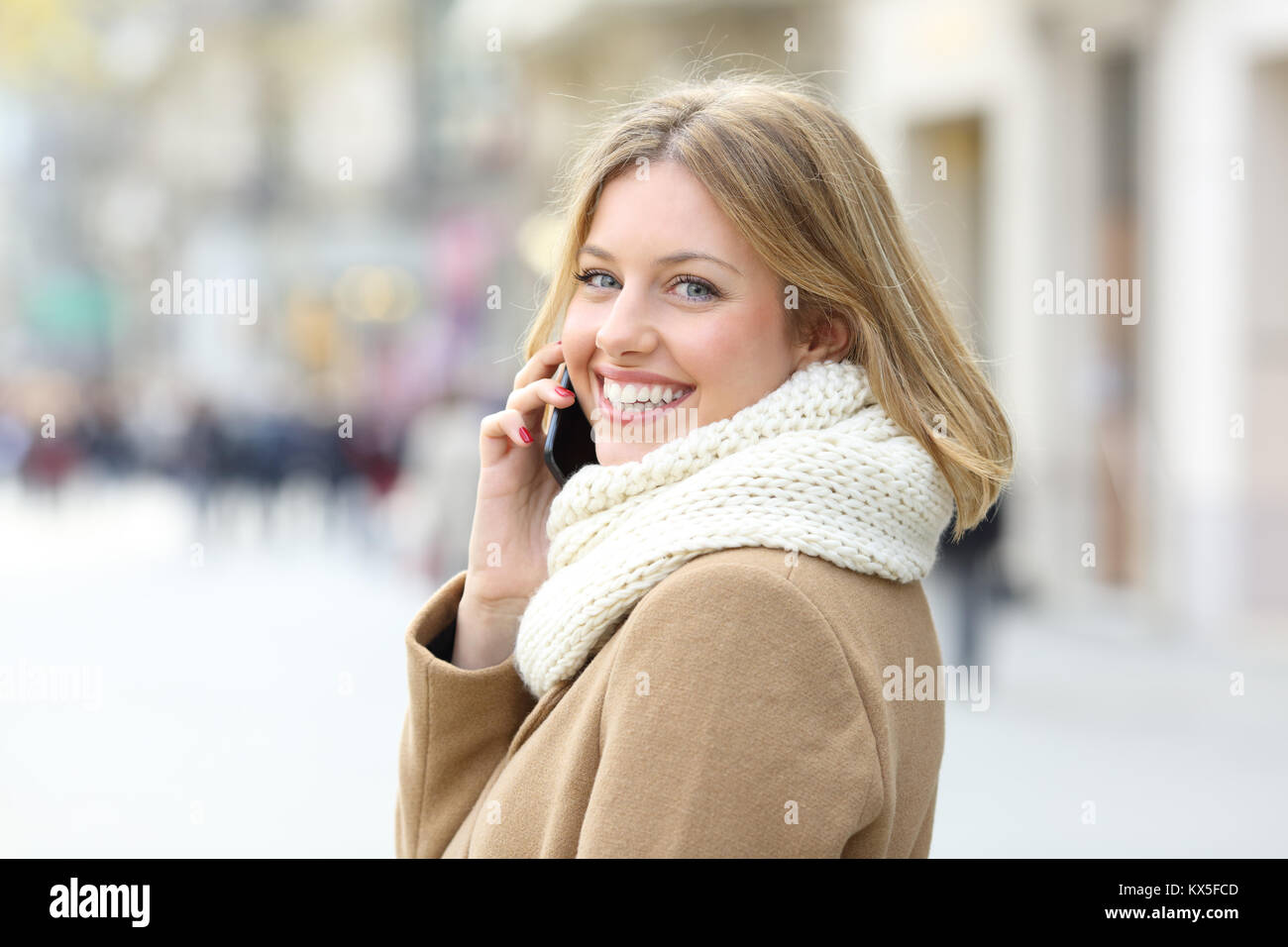 Heureux dame appelant sur téléphone mobile et vous regarde dans la rue en hiver Banque D'Images