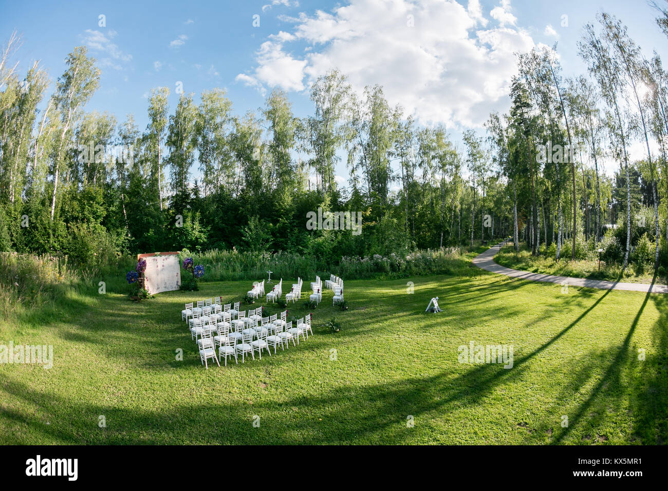 Cadre magnifique pour la cérémonie de mariage en plein air attendent les mariés et les invités. Chaises blanches décorées de fleurs, sont dans la zone de la cérémonie de mariage dans une forêt Banque D'Images