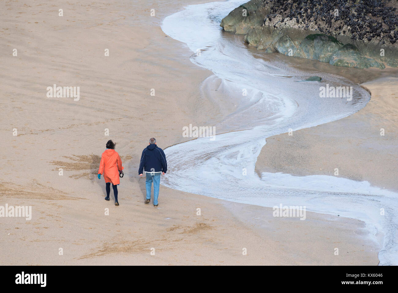 Un couple de personnes marchant sur une plage à marée basse. Banque D'Images