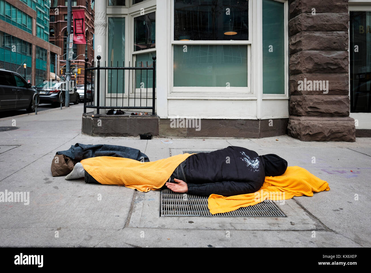 Crise du logement, homme sans-abri dormant en public sur le trottoir couvert de couverture dans le centre-ville de Toronto, Ontario, Canada. Banque D'Images