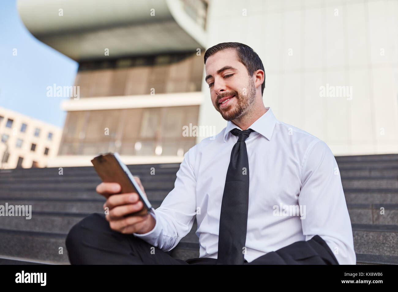 Jeune businessman reading message SMS sur smartphone Banque D'Images