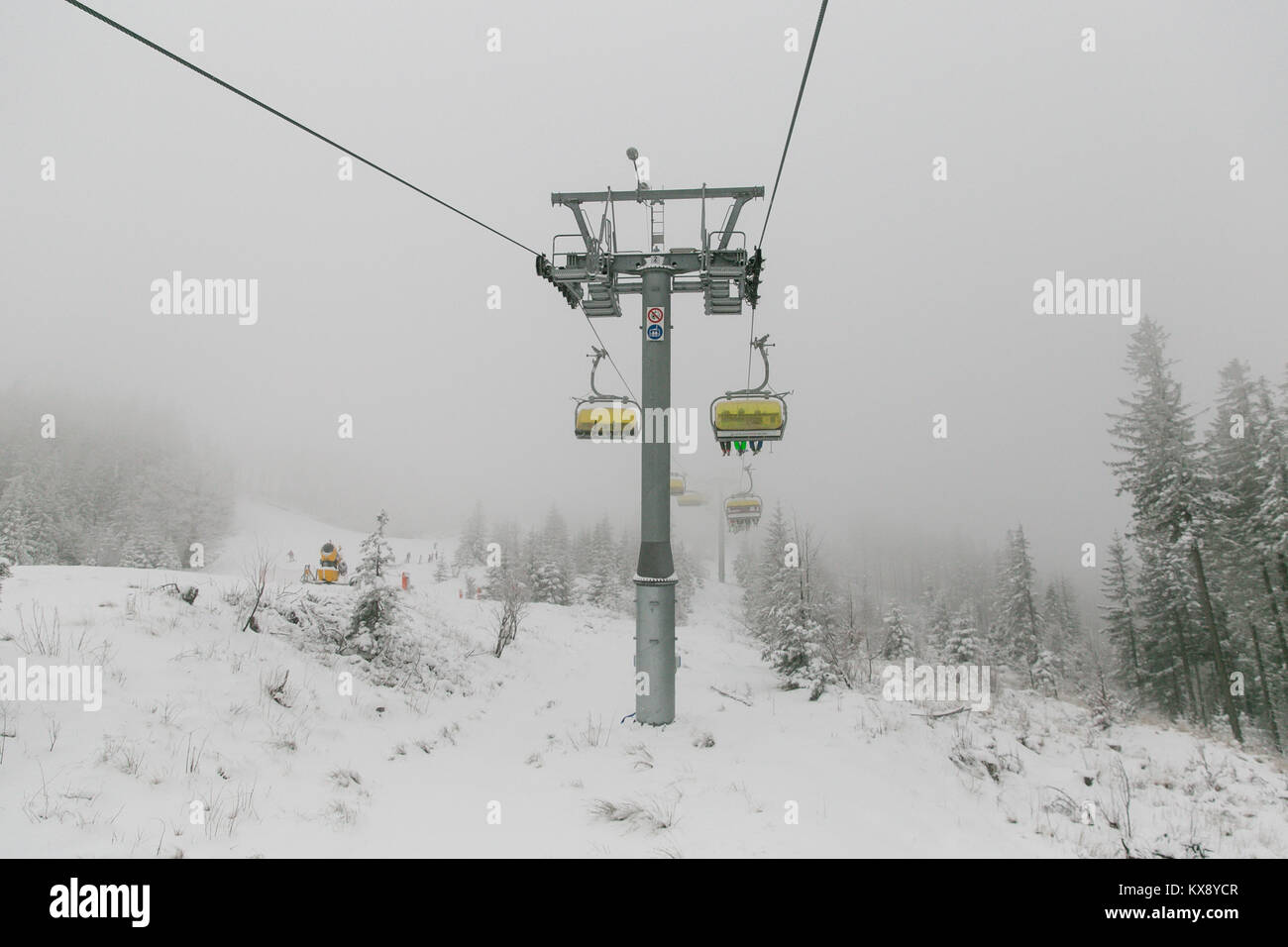 Télésiège de ski réunissant les skieurs et les surfeurs de la montagne Skrzyczne après les fortes chutes de neige sur une journée d'hiver brumeux de ski à Szczyrk en Pologne Banque D'Images