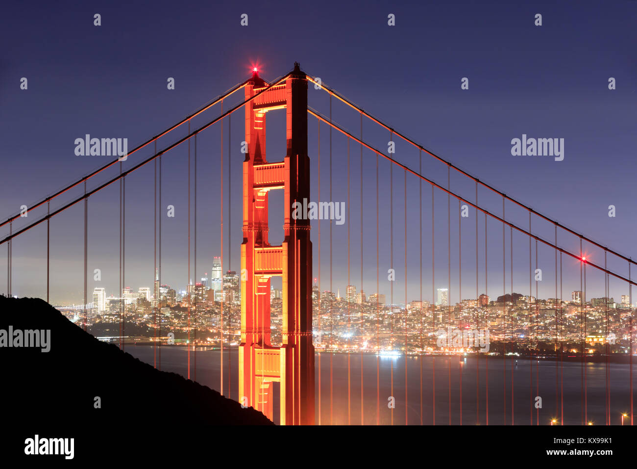 Golden Gate Bridge Close-up avec l'horizon de San Francisco sur fond clair une nuit d'hiver. Banque D'Images