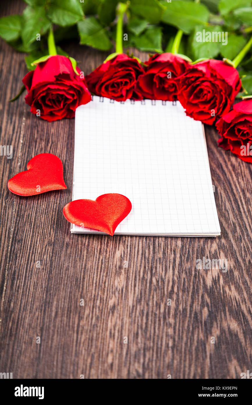 Roses rouges et carte sur un fond de bois. Carte de souhaits avec la Saint-Valentin, anniversaire ou mariage. Banque D'Images Roses rouges et carte sur un fond de bois. Carte de souhaits avec la Saint-Valentin, anniversaire ou mariage. Banque D'Images