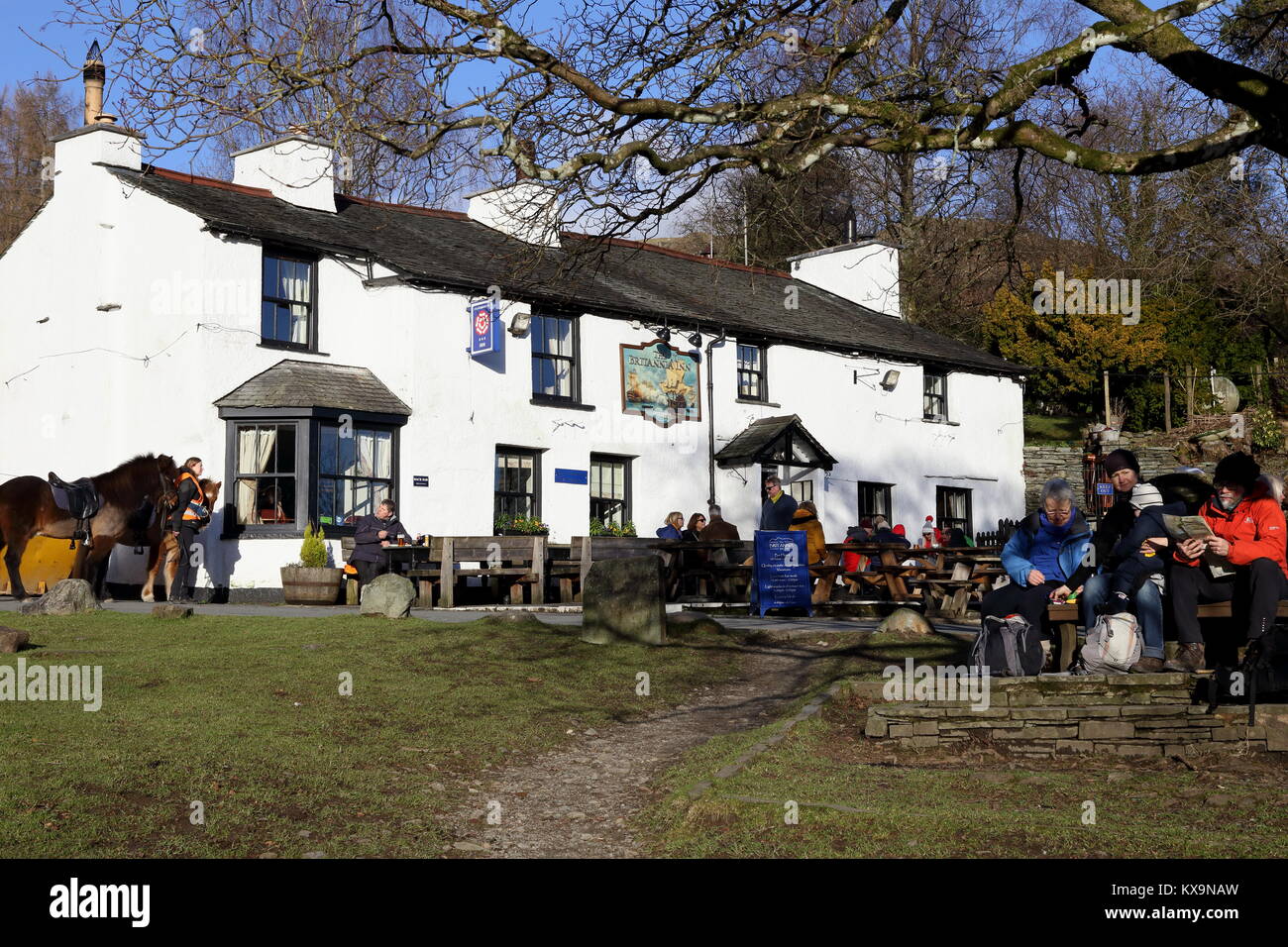 Les visiteurs apprécient un dimanche ensoleillé en janvier à l'extérieur de la Britannia Inn at Lake Road dans le Parc National de Lake District, Cumbria. Banque D'Images