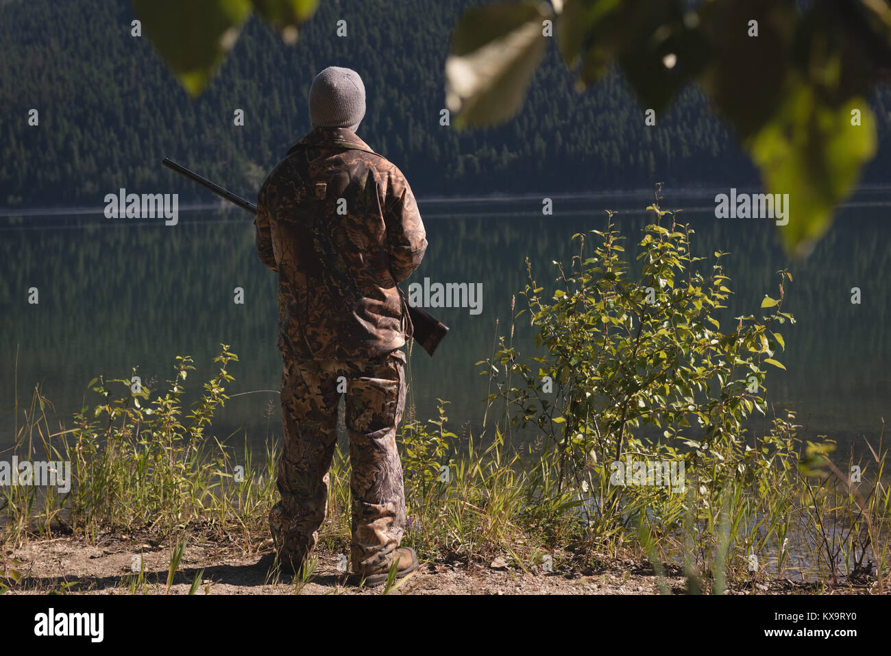 Hunter avec fusil debout près du lac Banque D'Images