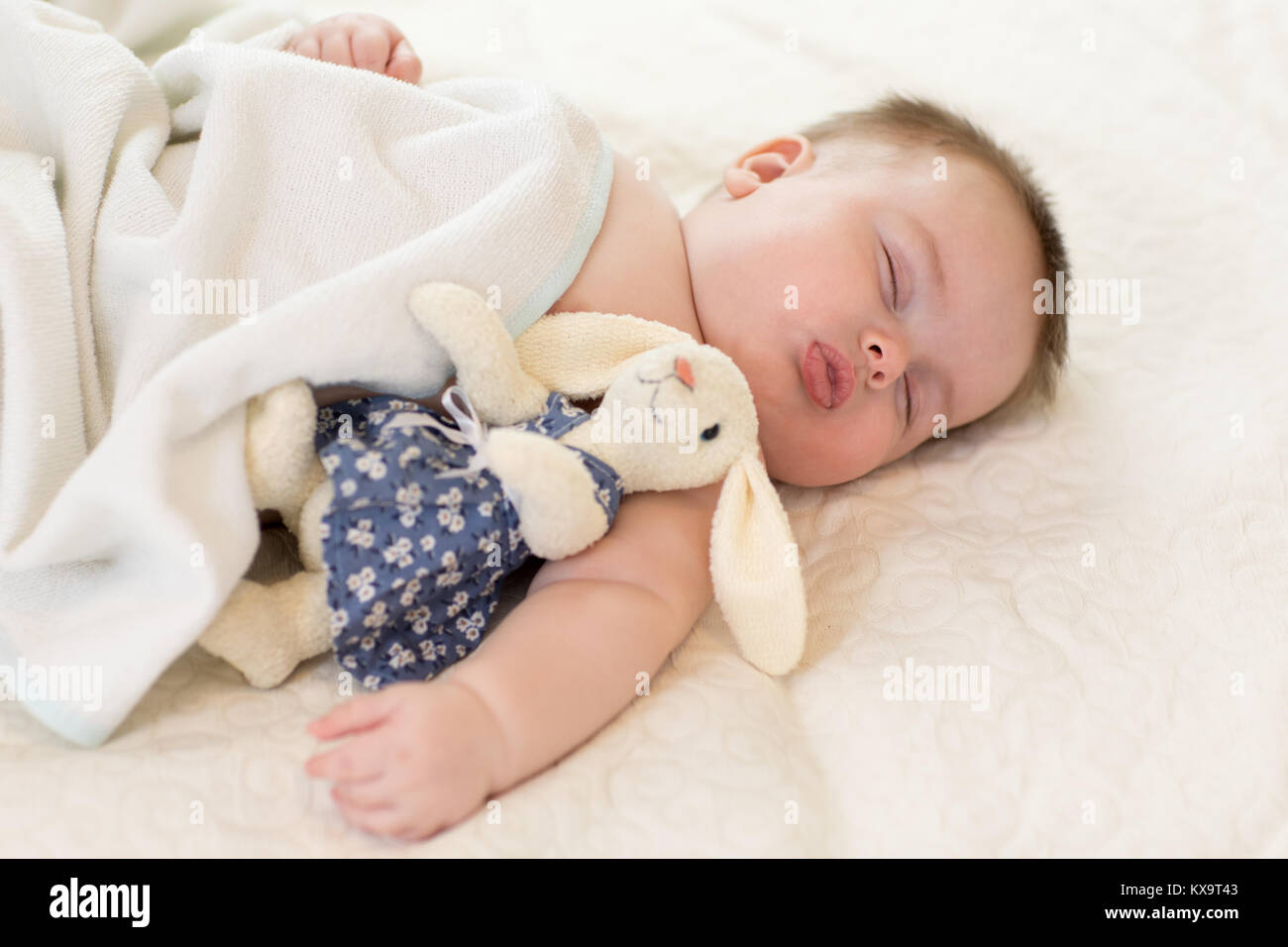 Mignon bébé nouveau-né avec couchage jouets sur le lit chez lui Banque D'Images
