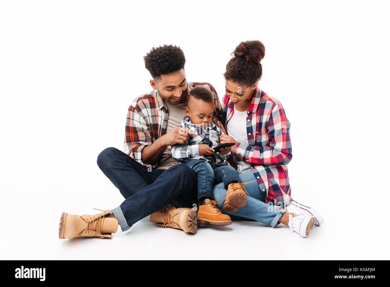 Portrait d'un jeune africain joyeuse famille avec leur petit-fils à l'aide de téléphone mobile tout en siégeant ensemble isolé sur fond blanc Banque D'Images