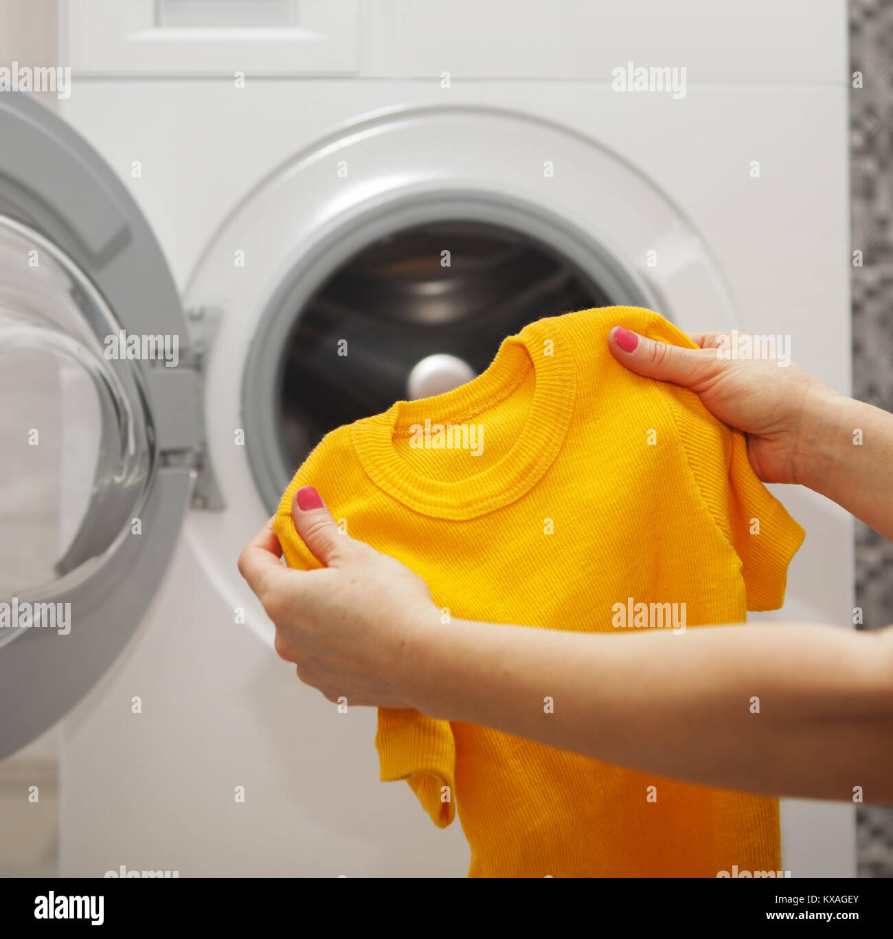 T-shirt en tricot dans les mains d'une femme qui va le laver en machine à laver Banque D'Images