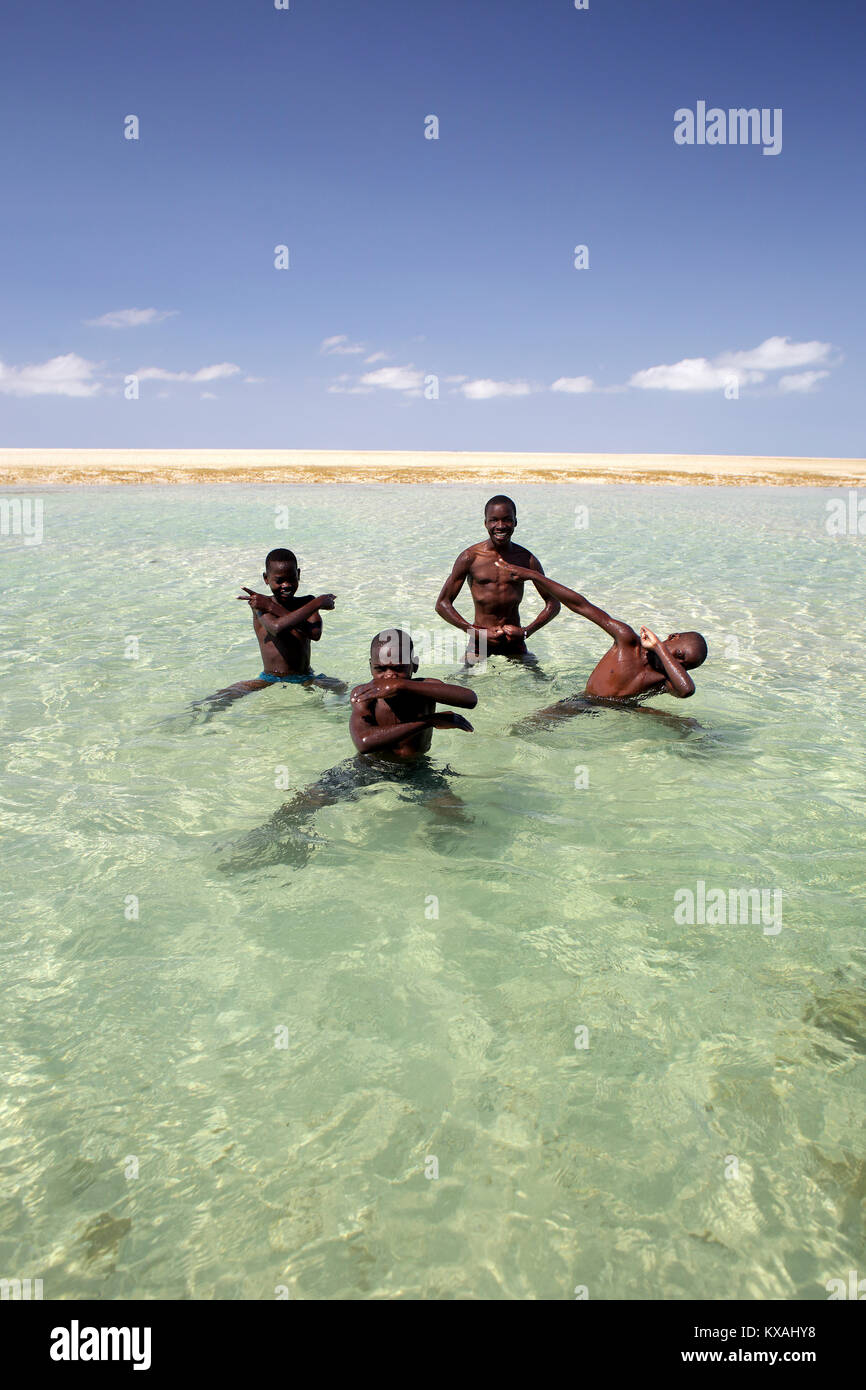 Quatre garçons qui posent ensemble dans l'eau côtière, au Mozambique Banque D'Images