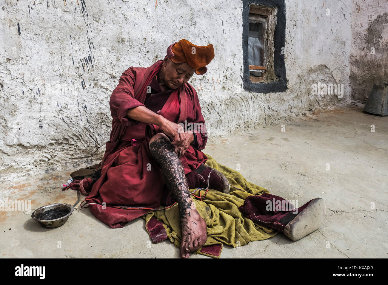 Moine de la secte Gelugpa l'application d'onguent sur sa jambe blessée au monastère de Rangdum, région du Ladakh, le Jammu-et-Cachemire, l'Inde Banque D'Images