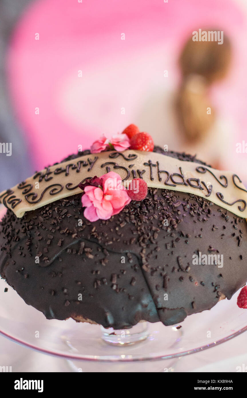 Joyeux anniversaire gâteau au chocolat sur la plaque en verre avec décoration de fleurs roses et fruits rouges Banque D'Images