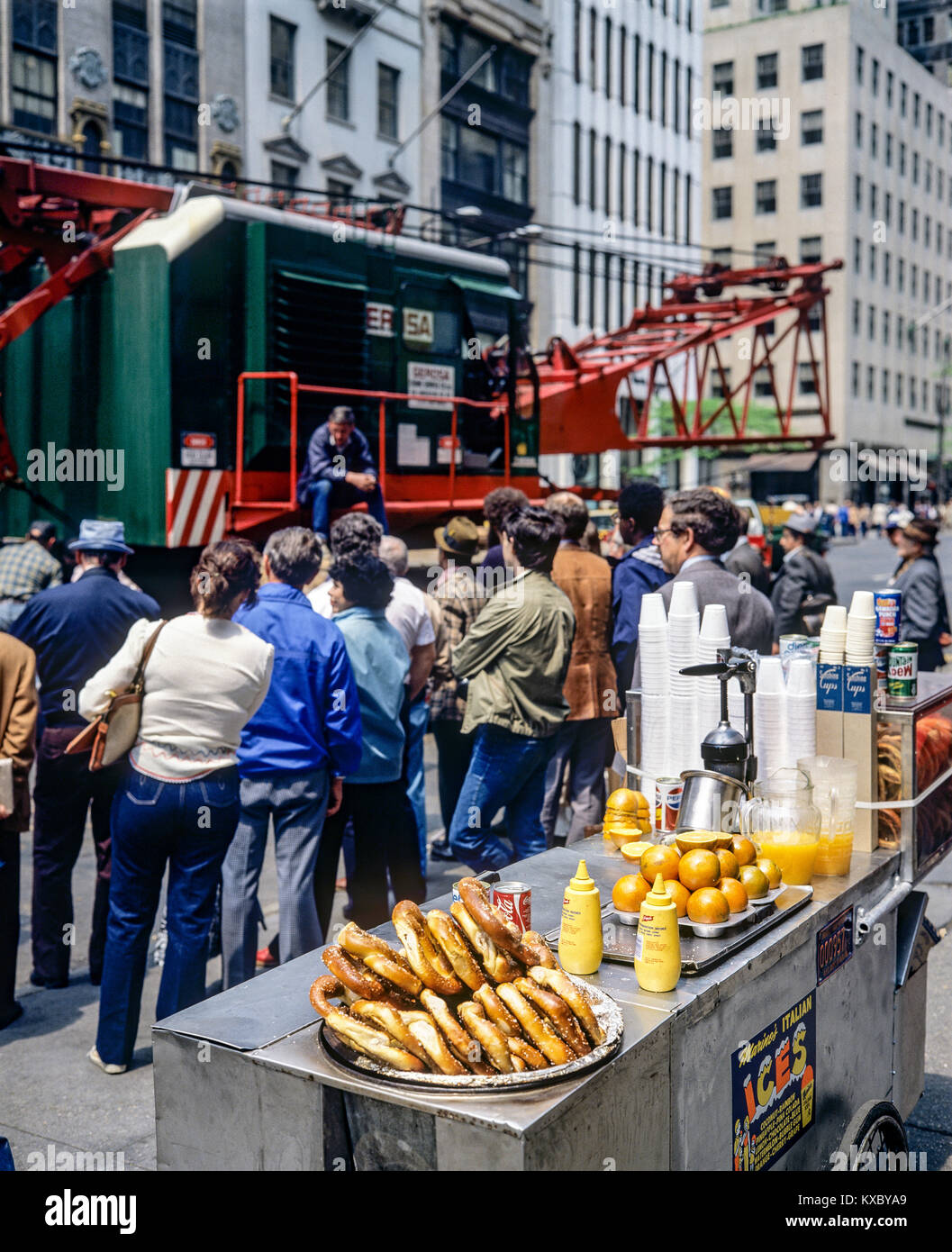 New York 1980s, chariot mobile de vente de nourriture, bretzels chauds, jus d'orange, les gens regardent la mise en place d'une grue, Manhattan, New York City, NY, NYC, ÉTATS-UNIS, Banque D'Images