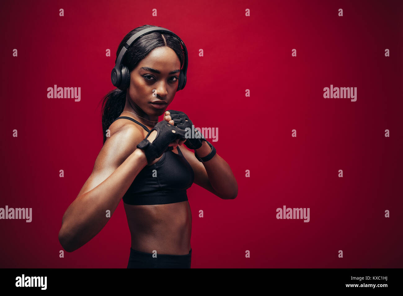 Femme noire difficiles avec un casque en position de combat permanent. African boxer exerçant sur fond rouge Banque D'Images