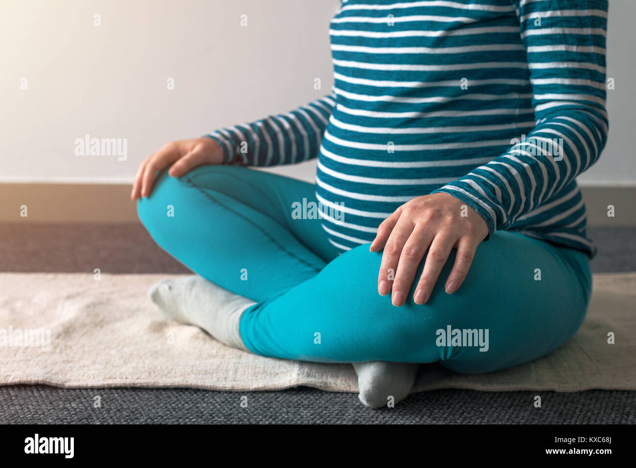 Pregnant woman practicing yoga exercice à la maison. Le yoga et la grossesse à l'intérieur concept de remise en forme. Images à faible contraste hors cadre naturel avec la lumière de la fenêtre. Banque D'Images