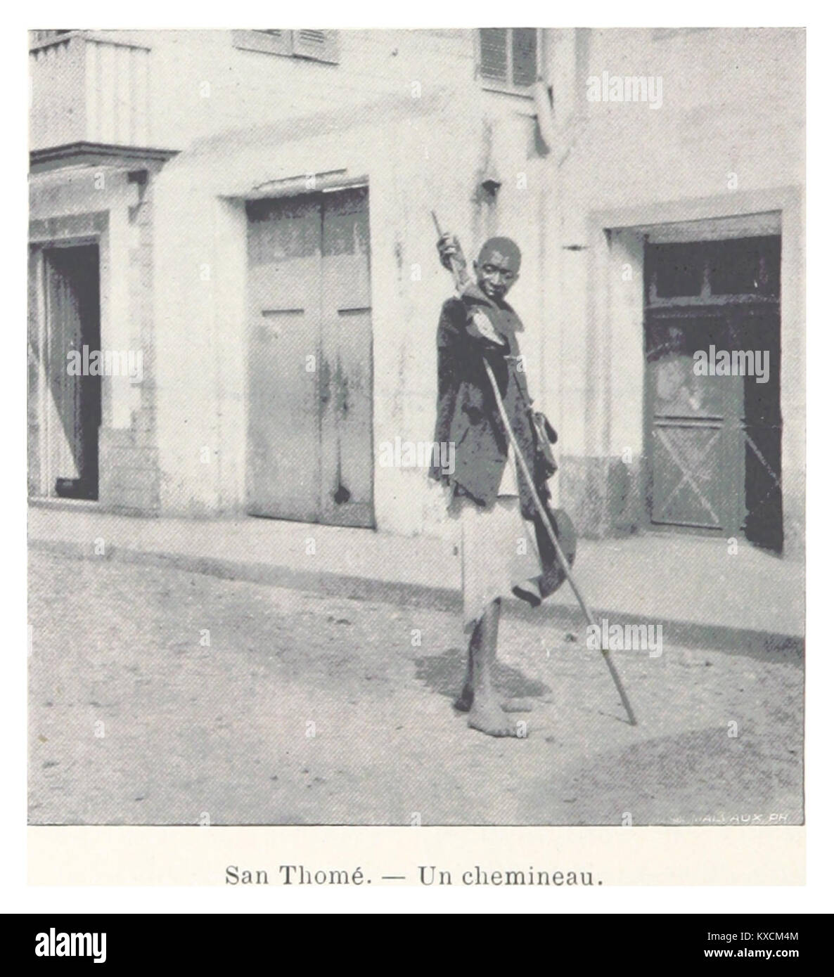 L'image montre un individu habillé en vagabond, capturant peut-être un moment de solitude ou voyageant le long d'une rue calme et rustique de San Thomé. Banque D'Images