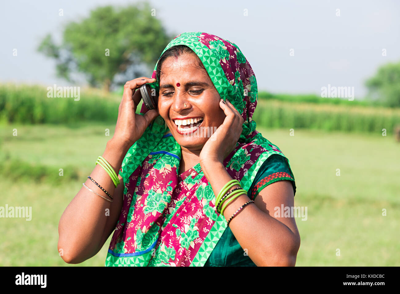 Femme rurale indienne Talking Cell Phone In Farm Happy Cheerful Banque D'Images