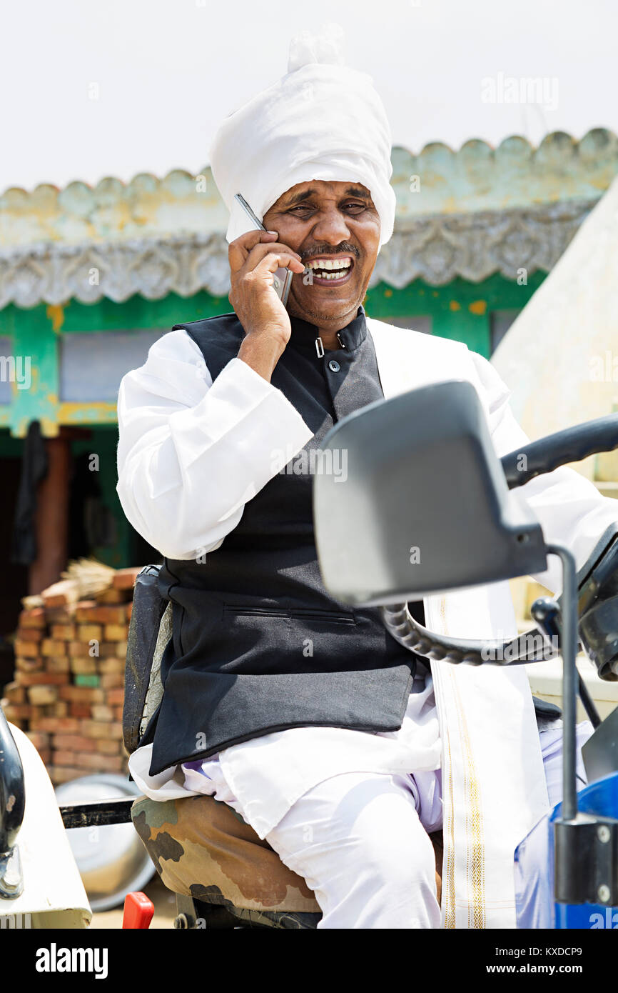 1 Les agriculteurs ruraux indiens parlant téléphone mobile tout en conduisant le tracteur Banque D'Images