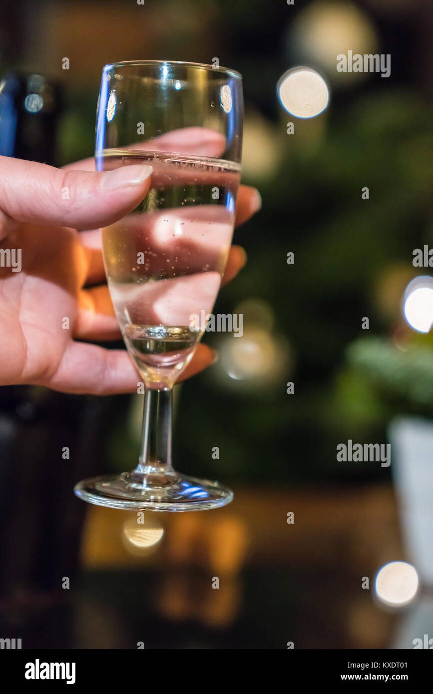 Une femme tient un verre de champagne avec un joint torique à l'intérieur Banque D'Images