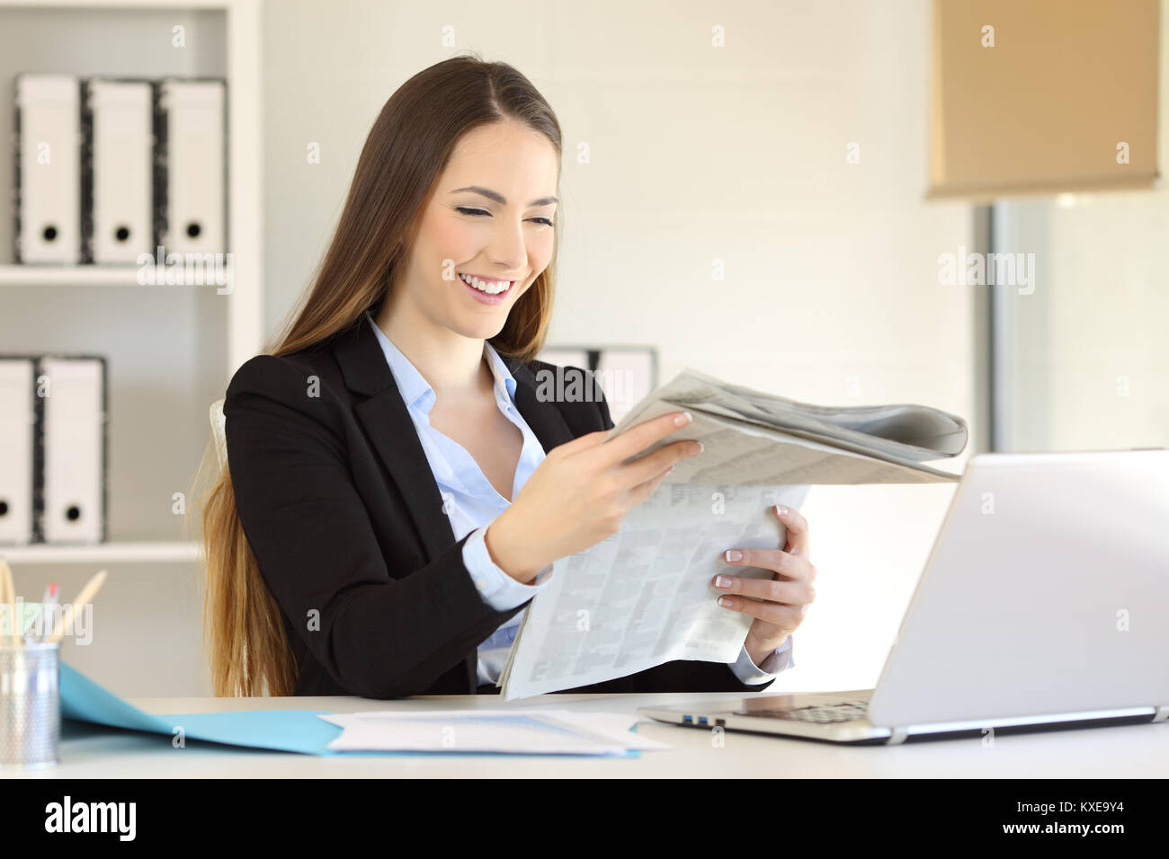 Heureux de la lire un journal assis dans un bureau à bureau Banque D'Images