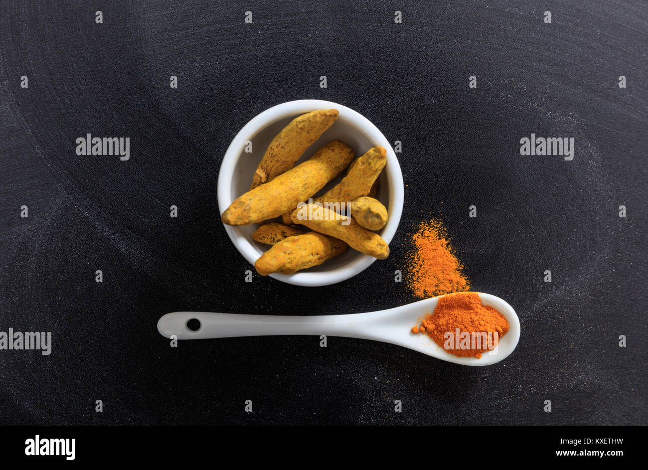 Bol en porcelaine de curcuma et une cuillère, fond noir Banque D'Images