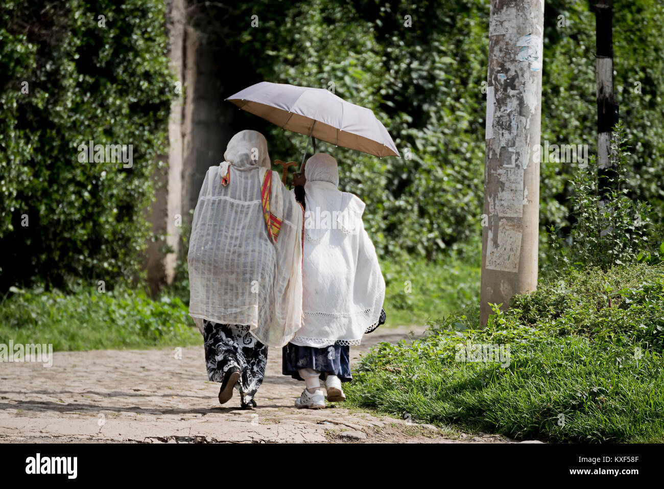 Deux femmes orthodoxes éthiopiens wearing white caps en direction de l'église avec parapluie dans Addis Ababa Ethiopie Banque D'Images