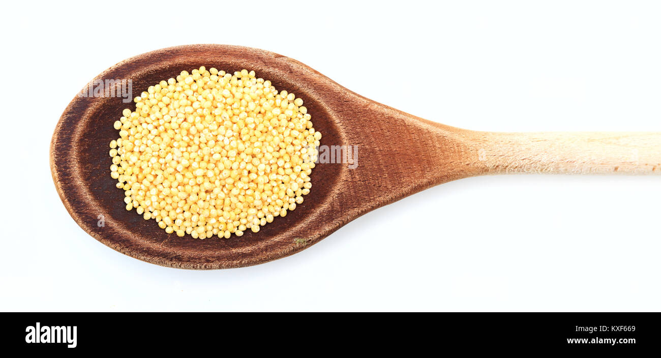 Millet dans une cuillère en bois sur fond blanc Banque D'Images