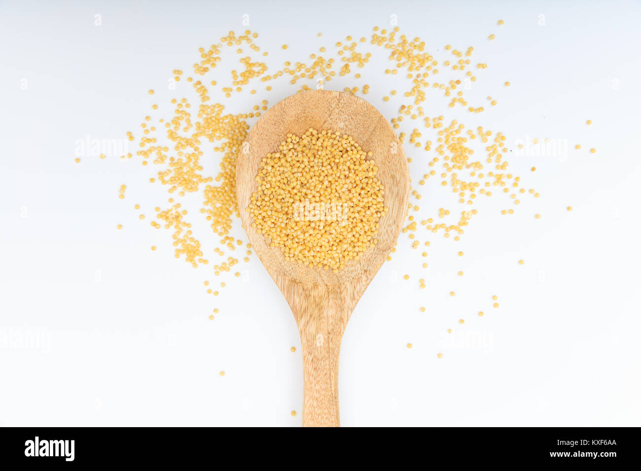 Graines de millet dans une cuillère en bois sur fond blanc Banque D'Images