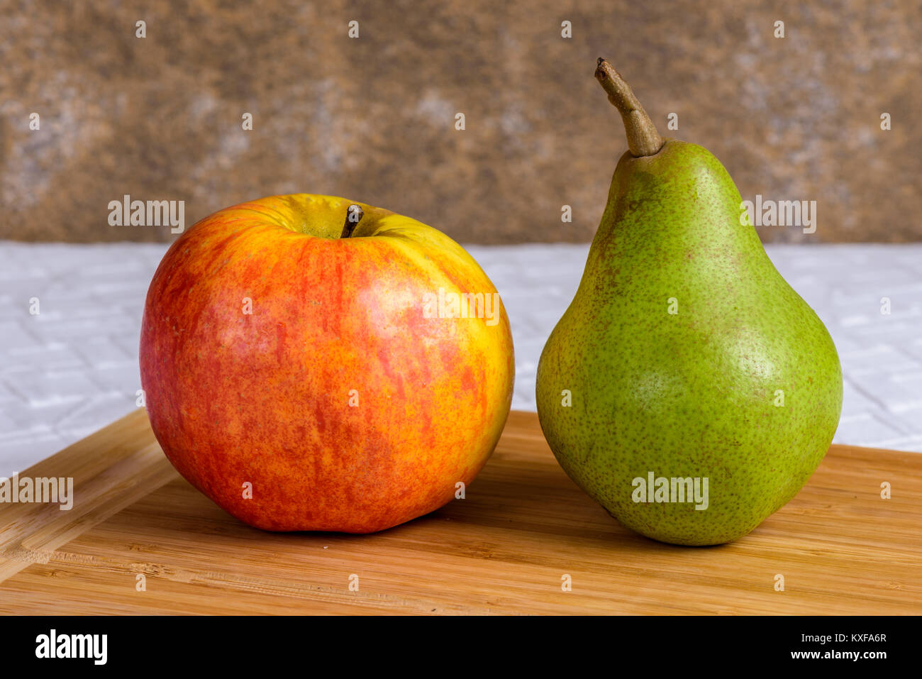 La vie encore d'une pomme et une poire sur une planche à découper en bois. Banque D'Images