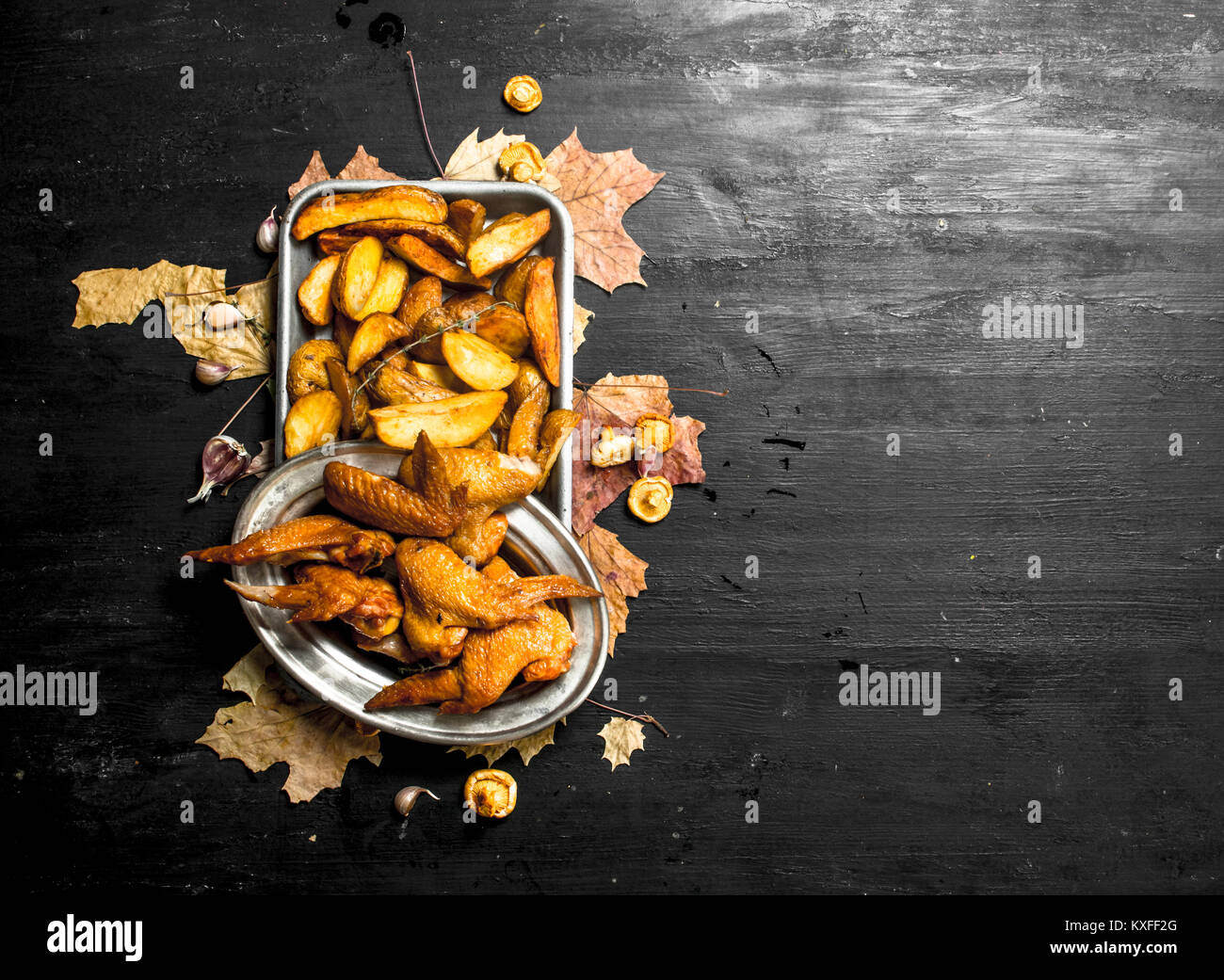 Ailes de poulet fumé avec des pommes de terre rissolées. Sur le tableau noir. Banque D'Images