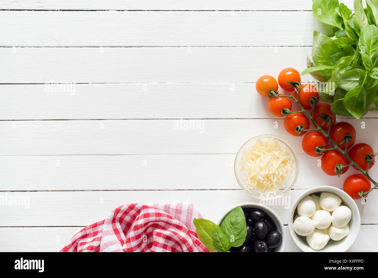 Les ingrédients alimentaires pour la cuisine italienne sur le tableau blanc. Le fromage parmesan, tomates cerises, olives, fromage mozzarella et basilic. Ingrédients Pizza Banque D'Images