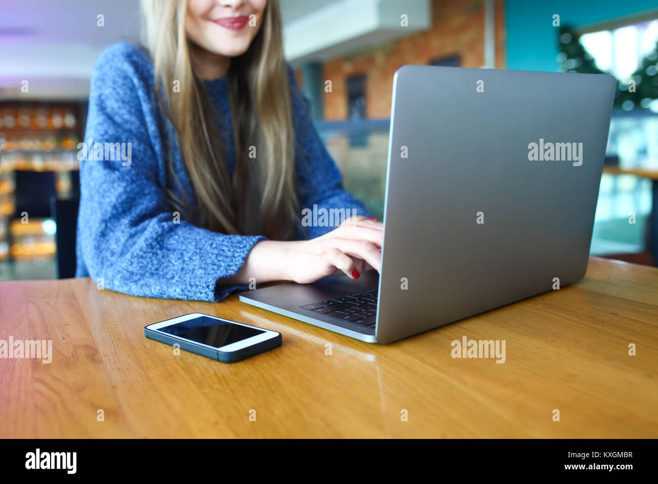 Woman working on laptop dans un café. Jeune femme assise à une table avec une usinglaptop. Avec copie vierge d'éboulis de l'espace pour votre publicité message texte ou image aux couleurs de contenu promotionnel. Focus sélectif. Banque D'Images