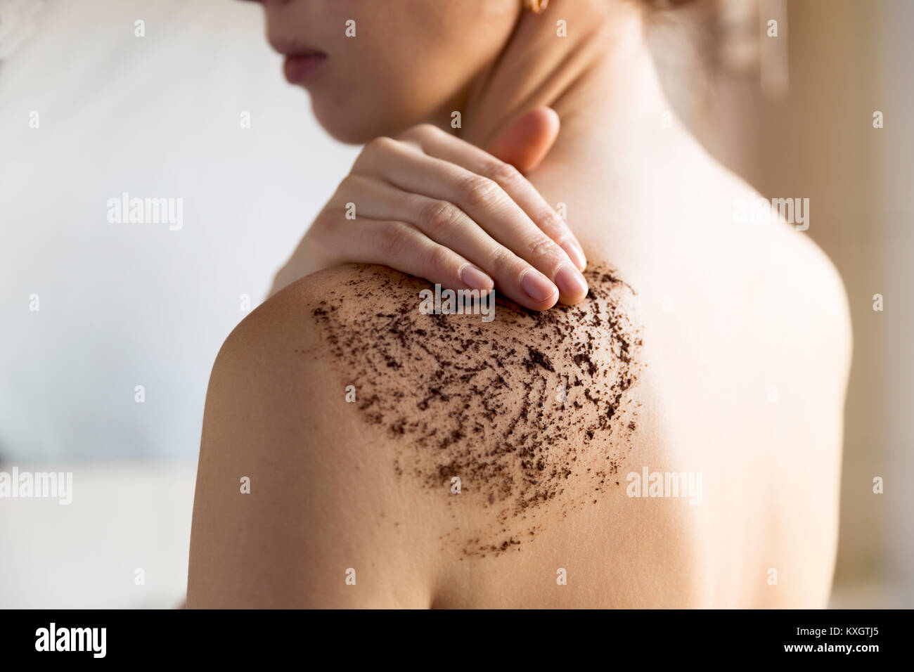 Beauté, spa et la peau saine notion - femme nettoie la peau du corps avec gommage café dans la salle de bains. Banque D'Images