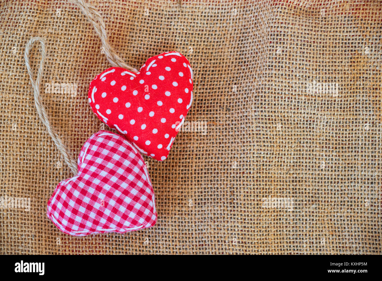 Deux coeurs en tissu rouge sur fond de toile rustique Banque D'Images