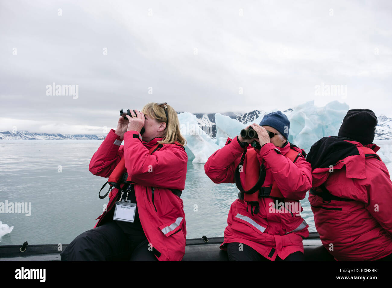 G Adventures passagers de navires de croisière observation de la faune à l'aide de jumelles sur un zodiac canot dans les eaux de l'Arctique glacial. Spitsbergen, Svalbard, Norvège Banque D'Images