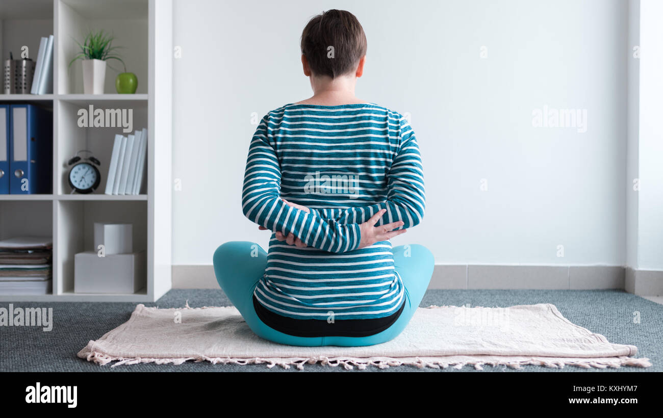 Pregnant woman practicing yoga exercice à la maison. Le yoga et la grossesse à l'intérieur concept de remise en forme. Images à faible contraste hors cadre naturel avec la lumière de la fenêtre. Banque D'Images